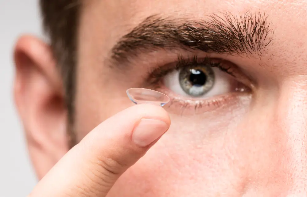 Close-up of a person positioning a contact lens near their eye.